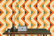 Load image into Gallery viewer, Bold orange and blue geometric retro vintage fabric peel and stick wallpaper with table, clock and plant