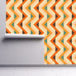 Load image into Gallery viewer, Bold orange and blue geometric retro vintage fabric peel and stick wallpaper on wall partially rolled up