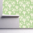 Load image into Gallery viewer, Light green English Chinoiserie botanical fabric peel and stick wallpaper on wall partially rolled up