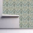 Load image into Gallery viewer, Antique Victorian damask floral grey fabric peel and stick wallpaper on wall with partial roll rolled up
