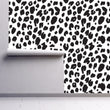 Load image into Gallery viewer, Black and white leopard print fabric peel and stick wallpaper on wall partially rolled up
