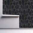 Load image into Gallery viewer, Moody dark Art Deco black and gold fabric peel and stick wallpaper on wall partially rolled up
