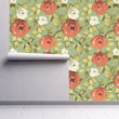 Load image into Gallery viewer, Antique pink and green floral fabric peel and stick wallpaper on wall partially rolled up
