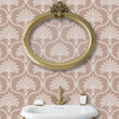 Load image into Gallery viewer, Pink Victorian antique damask fabric peel and stick wallpaper in bathroom with gold mirror and sink
