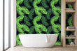 Load image into Gallery viewer, Neon green tropical palm leaves fabric peel and stick wallpaper in bathroom with bathtub and shelves
