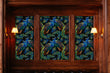 Load image into Gallery viewer, Black and blue dark topical botanical peacock fabric peel and stick wallpaper on wood wall with sconces
