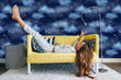 Load image into Gallery viewer, Blue night sky clouds and starts fabric wallpaper in room with girl laying on sofa
