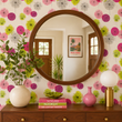 Load image into Gallery viewer, A round walnut mirror creates a striking focal point in this mid-century entryway featuring Stella Road wallpaper by Pickwick &amp; Elm with playful retro botanical circles in pink, green, and gray.
