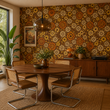 Load image into Gallery viewer, A walnut dining table and cane chairs are framed by the Sydney Place wallpaper from Pickwick &amp; Elm, adding colorful retro floral character to this mid-century dining room.
